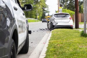 Police vehicle at the scene of a rear-end collision with a damaged car.