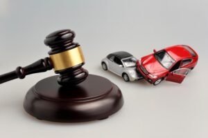 Judge's gavel with miniature cars representing a car accident on a gray background.