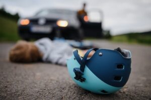 Little boy fallen from bicycle and lying still on road after car accident.