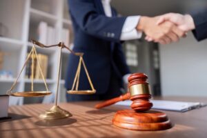 Professional lawyer shaking hands in a business meeting, with scales of justice and a gavel on the desk, symbolizing legal agreements and partnerships.