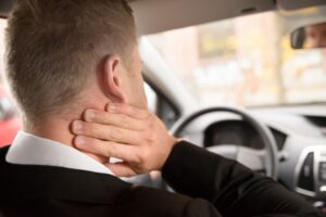 Rear View Of A Man Having Neck Pain While Driving A Car